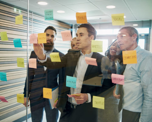 Group of business people brainstorming Group of business people brainstorming with sticky notes on glass window